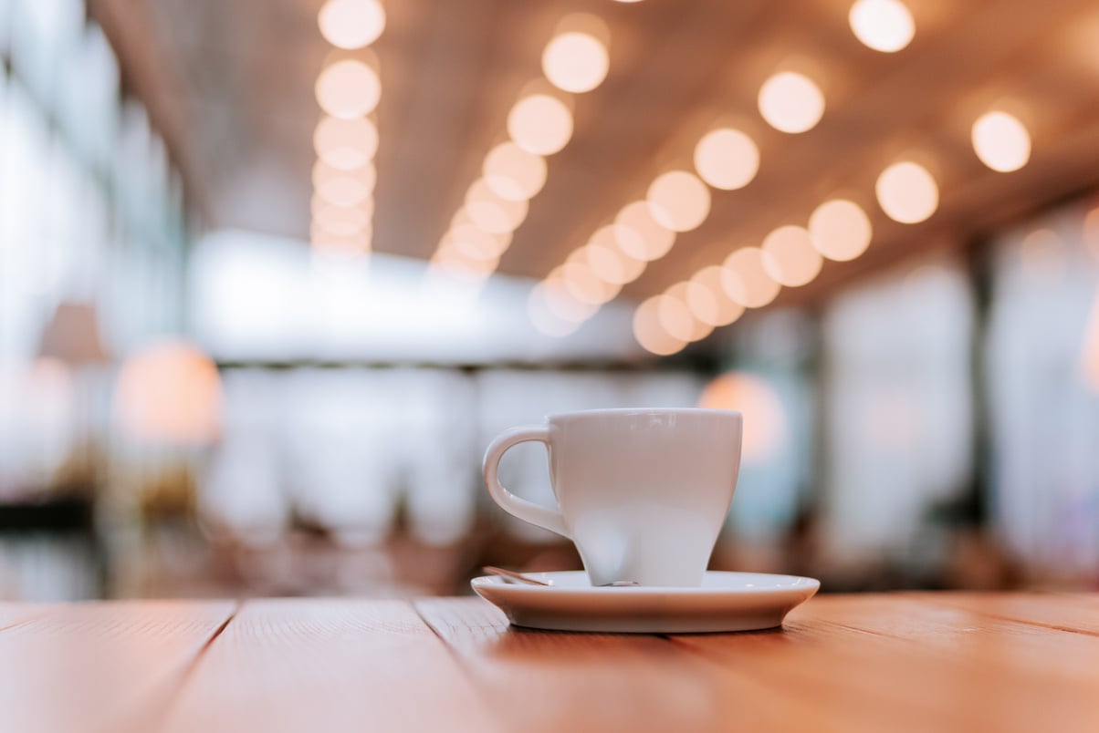 Coffee shop interior, coffee cup on wooden table.