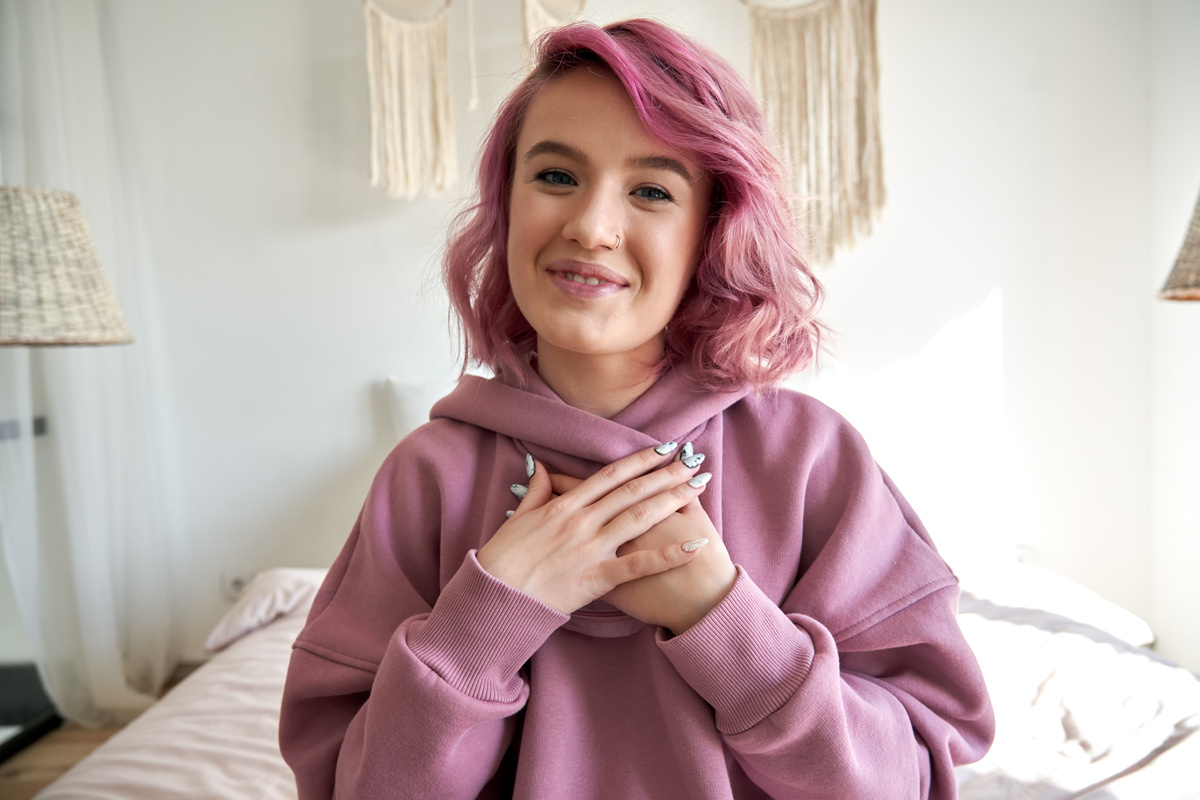 Happy hipster gen z teen girl blogger pink hair looking at camera record vlog.